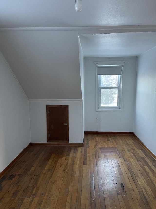 bonus room with dark hardwood / wood-style floors and vaulted ceiling