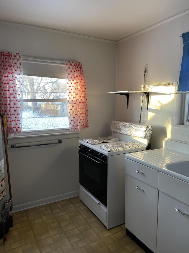 kitchen with white cabinets, crown molding, sink, and white gas range oven