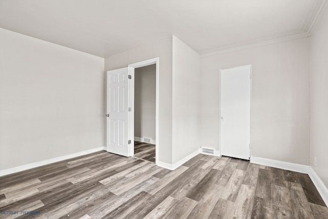 empty room with ornamental molding and hardwood / wood-style floors