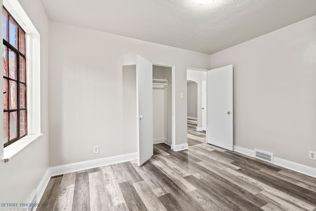 unfurnished bedroom with multiple windows, hardwood / wood-style flooring, and a closet