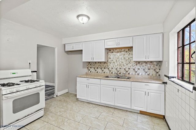 kitchen with white cabinetry, sink, tile walls, white range with gas cooktop, and a textured ceiling