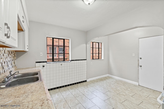 kitchen featuring tile walls, sink, light tile patterned floors, and white cabinets