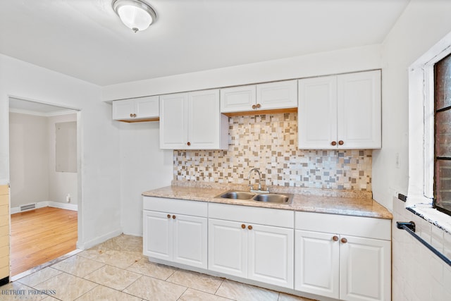 kitchen with tasteful backsplash, sink, light tile patterned floors, and white cabinets