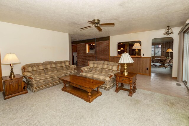 21734 N Channel Pkwy, Edwardsburg, MI 49112 - carpeted living area featuring a ceiling fan, a textured ceiling, a wainscoted wall, arched walkways, and tile patterned floors