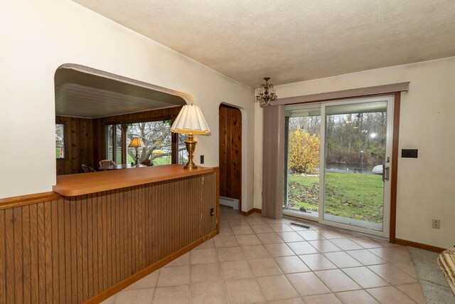 21734 N Channel Pkwy, Edwardsburg, MI 49112 - kitchen with a baseboard heating unit, plenty of natural light, arched walkways, a chandelier, and wooden walls