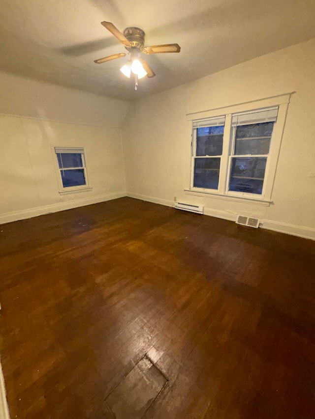 spare room featuring ceiling fan, dark wood-type flooring, and a baseboard heating unit