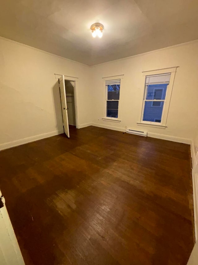 unfurnished room with dark hardwood / wood-style flooring and a baseboard radiator