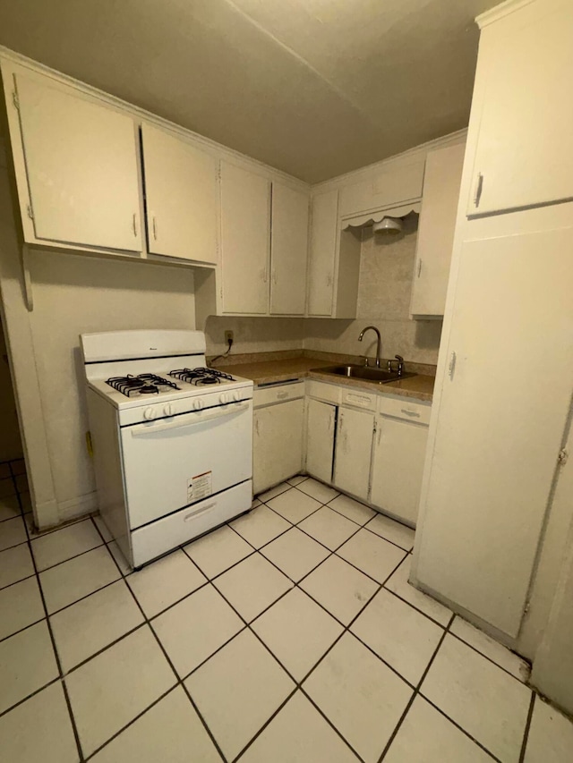 kitchen with light tile patterned floors, white appliances, white cabinetry, and sink