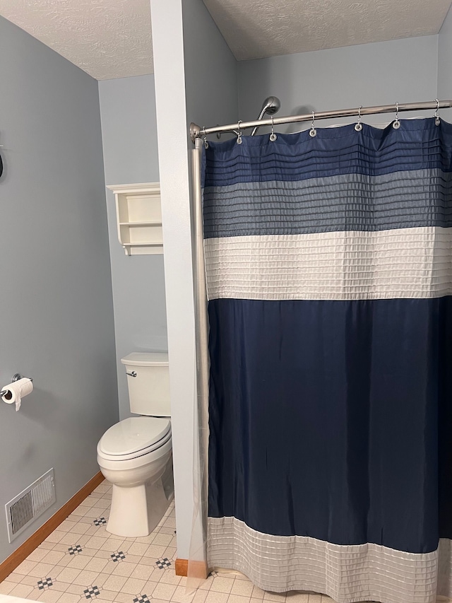 bathroom with toilet, a shower with shower curtain, and a textured ceiling