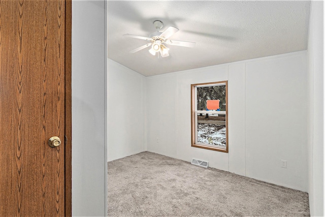 carpeted spare room with ceiling fan and a textured ceiling