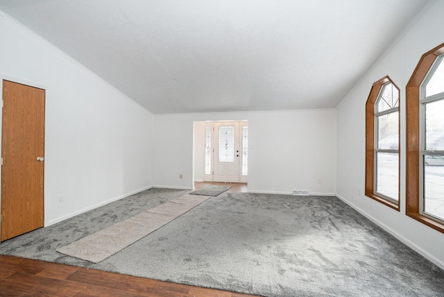 unfurnished room featuring visible vents, baseboards, carpet floors, vaulted ceiling, and wood finished floors