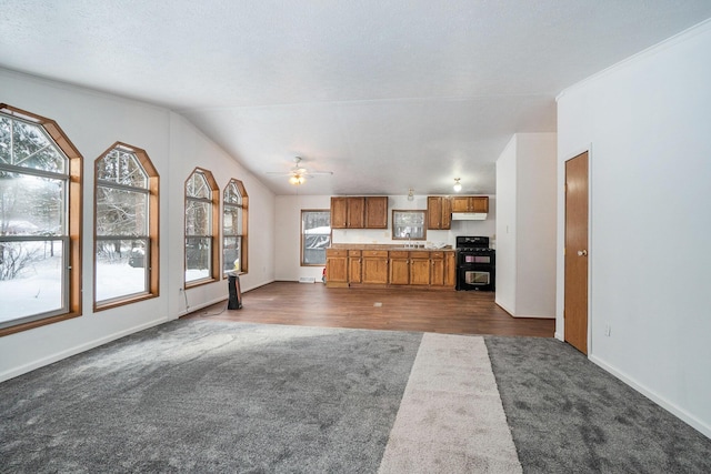 unfurnished living room featuring dark colored carpet, baseboards, ceiling fan, dark wood-style flooring, and vaulted ceiling