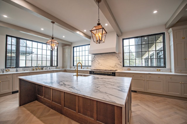 kitchen featuring pendant lighting, sink, light stone counters, an island with sink, and light parquet flooring