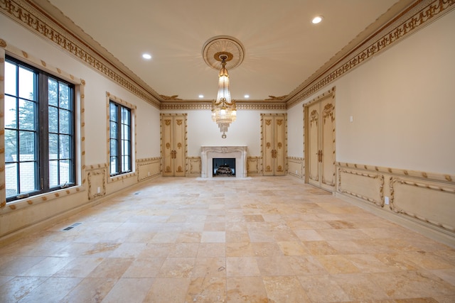 unfurnished living room with crown molding, a fireplace, and a chandelier