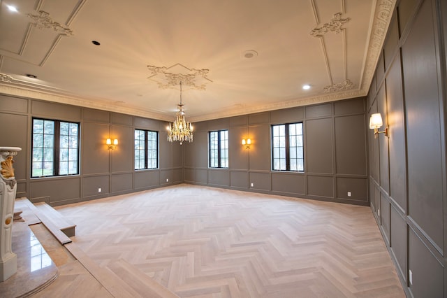 spare room featuring light parquet flooring, an inviting chandelier, and crown molding