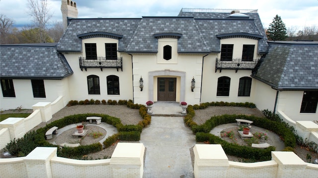 view of front of home with french doors and a balcony