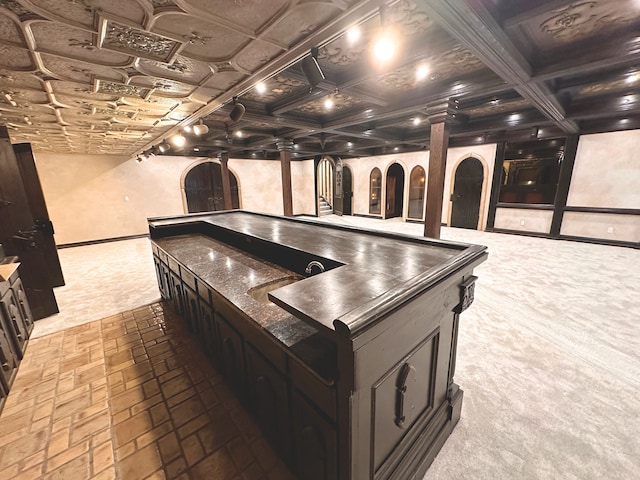 kitchen featuring coffered ceiling, beam ceiling, carpet, and ornate columns