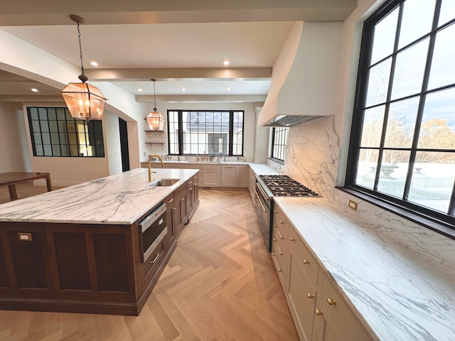 kitchen with sink, light stone counters, hanging light fixtures, custom range hood, and a large island