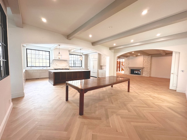 recreation room with beam ceiling, a fireplace, and light parquet flooring