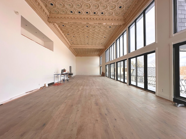 empty room featuring hardwood / wood-style flooring, a towering ceiling, and ornamental molding