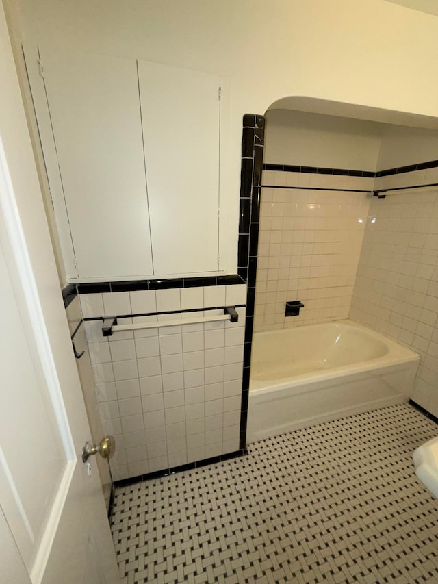 bathroom with tile patterned floors, tiled shower / bath combo, and tile walls