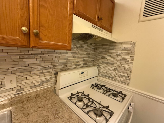 kitchen featuring light stone countertops, tasteful backsplash, and white range with gas cooktop