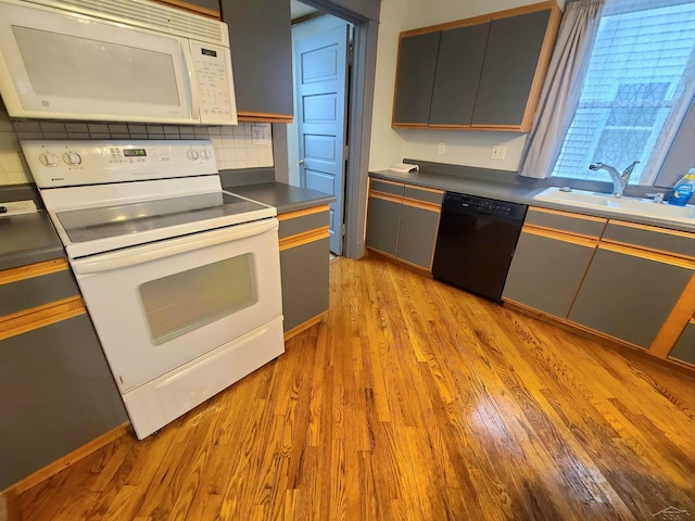 kitchen with white appliances, sink, backsplash, light wood-type flooring, and gray cabinetry