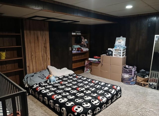 carpeted bedroom featuring wood walls