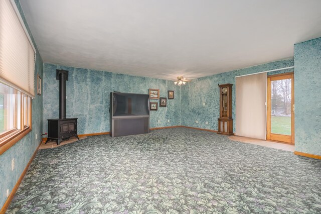 18980 16 Mile Rd, Marshall, MI 49068 - unfurnished living room featuring a wood stove, healthy amount of natural light, wallpapered walls, and carpet