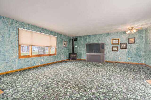 18980 16 Mile Rd, Marshall, MI 49068 - unfurnished living room featuring a wood stove, carpet floors, a ceiling fan, and baseboards