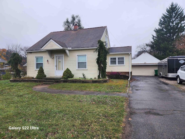 bungalow-style home with a garage, an outbuilding, and a front lawn