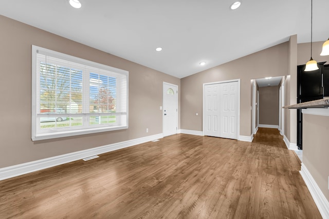 unfurnished living room with hardwood / wood-style floors and vaulted ceiling