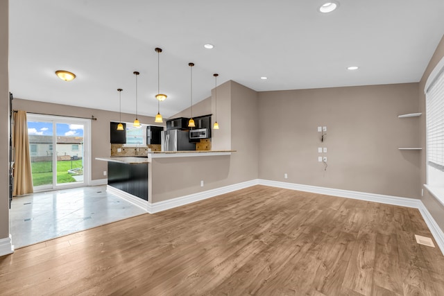 kitchen featuring pendant lighting, a breakfast bar, light hardwood / wood-style floors, kitchen peninsula, and stainless steel appliances