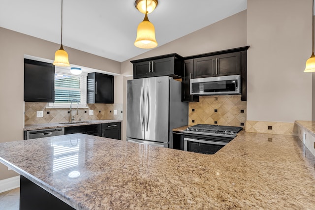 kitchen featuring kitchen peninsula, appliances with stainless steel finishes, decorative backsplash, sink, and decorative light fixtures