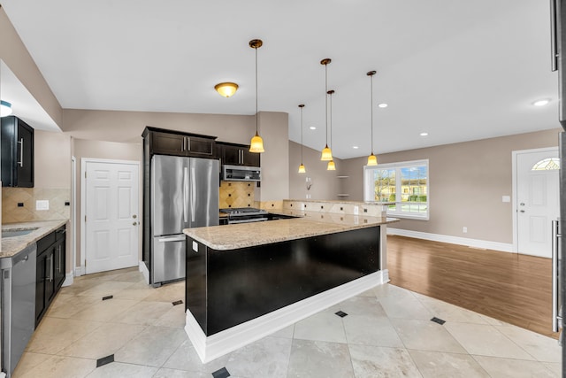 kitchen featuring light stone counters, light tile patterned flooring, decorative light fixtures, and appliances with stainless steel finishes