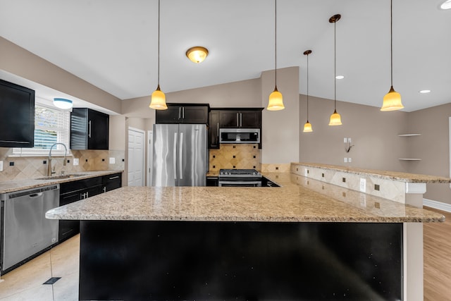 kitchen featuring kitchen peninsula, backsplash, stainless steel appliances, sink, and pendant lighting