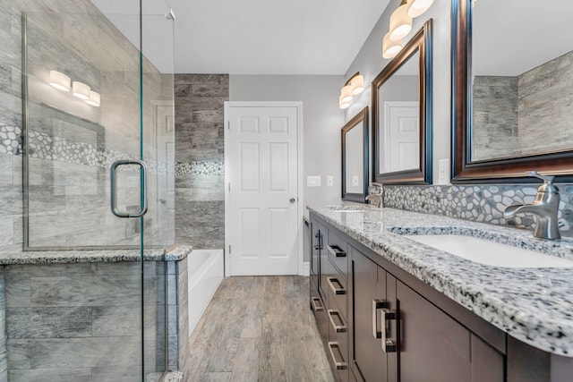 bathroom with tasteful backsplash, independent shower and bath, vanity, and wood-type flooring