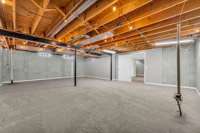 basement featuring carpet floors and brick wall