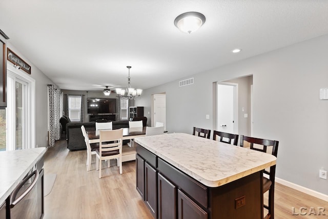 kitchen with dark brown cabinets, a center island, pendant lighting, and light wood-type flooring