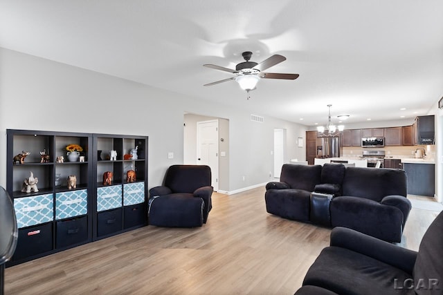 living room featuring sink, ceiling fan with notable chandelier, and light wood-type flooring