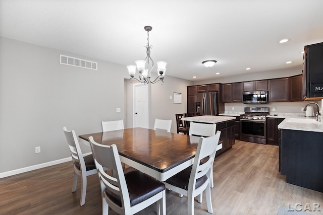 dining room with light hardwood / wood-style floors, an inviting chandelier, and sink