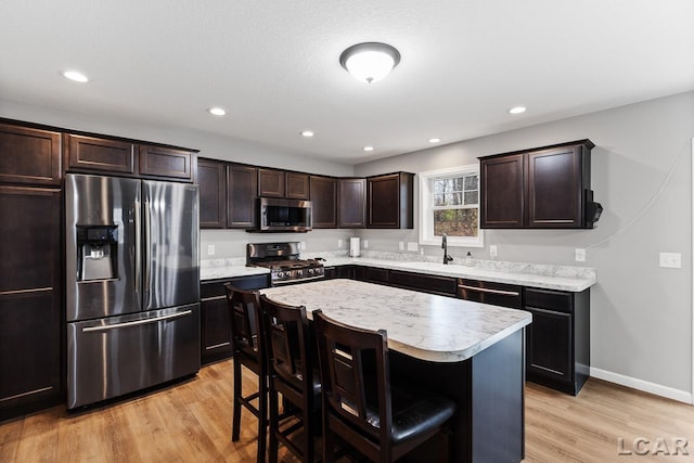 kitchen featuring a center island, sink, light hardwood / wood-style flooring, a kitchen bar, and stainless steel appliances