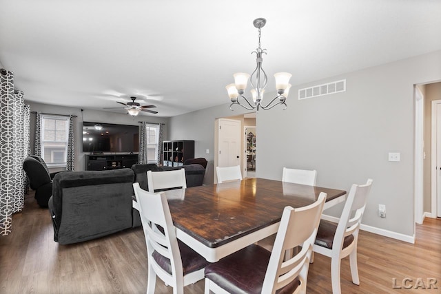 dining room with ceiling fan with notable chandelier and hardwood / wood-style flooring