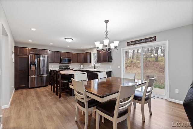 dining space featuring light hardwood / wood-style floors, sink, and a chandelier