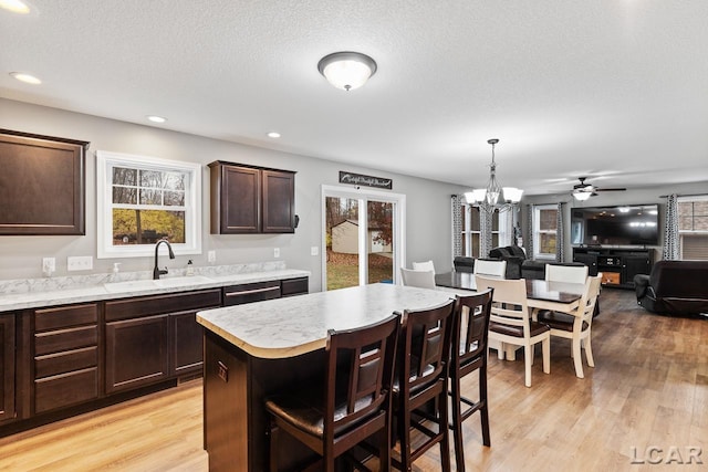 kitchen featuring decorative light fixtures, a kitchen island, sink, and a wealth of natural light