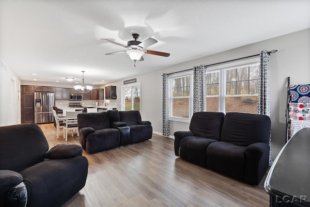 living room featuring light hardwood / wood-style flooring and ceiling fan with notable chandelier