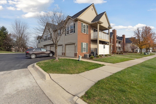 exterior space with cooling unit, a garage, a yard, and a balcony