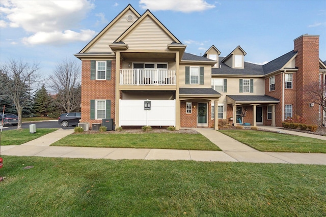 view of front of house featuring a front yard, a balcony, and cooling unit