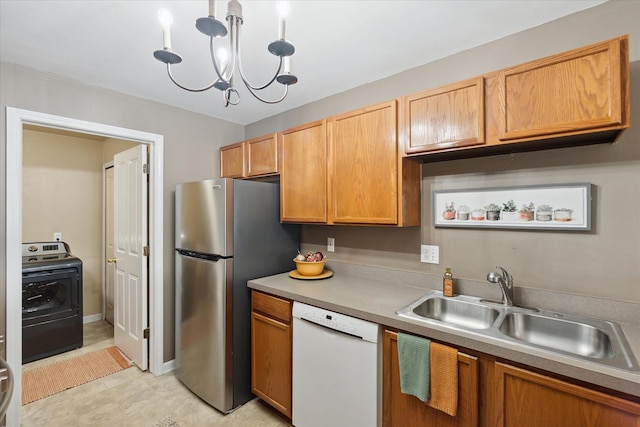 kitchen with sink, a notable chandelier, stainless steel fridge, white dishwasher, and washer / dryer