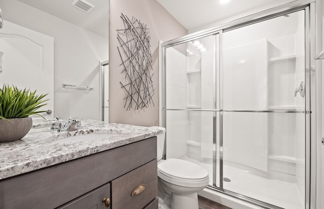 bathroom with vanity, a shower with shower door, and toilet